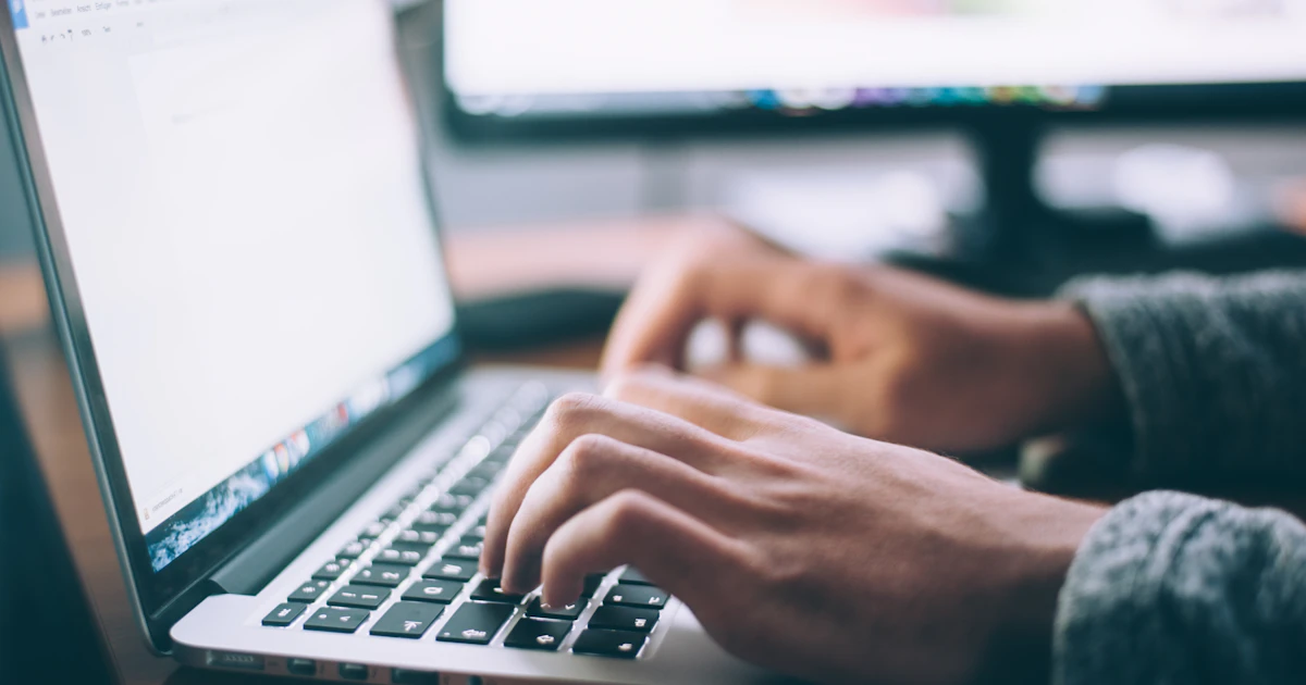 Hands typing on a laptop keyboard to enter the trademark symbol