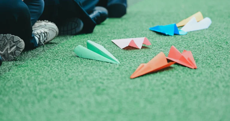 Colourful paper airplanes on green grass, like payments sent with a PayPal.Me link